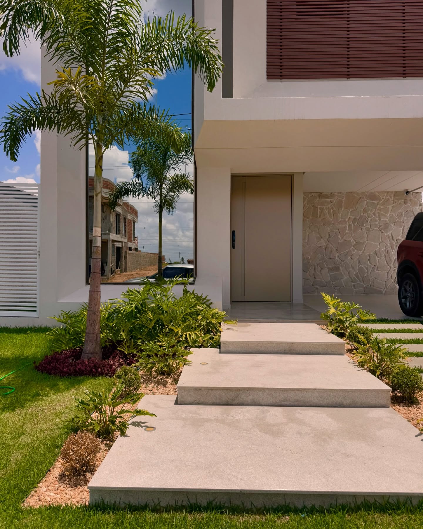 Entrada residencial com palmeiras e jardim